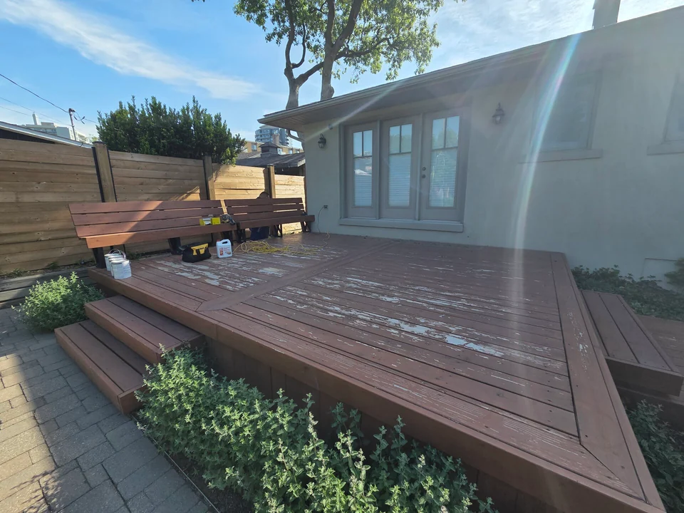 Before: backyard deck with worn finish beside glass patio doors