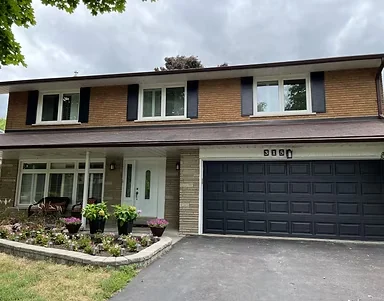 Two-storey brick home with dark garage door and contrasting white porch