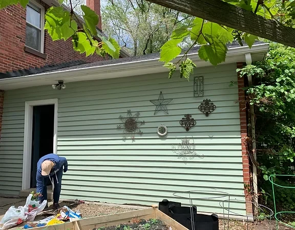 Finished pale green exterior siding beside a white trimmed window