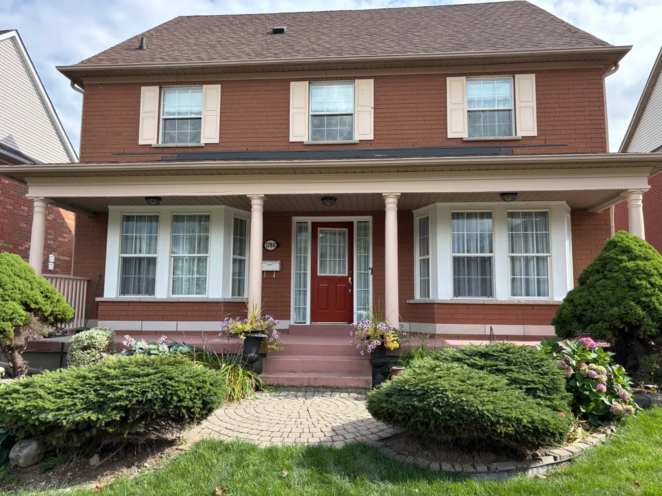 Front view of a brick home with white porch columns and red entrance door