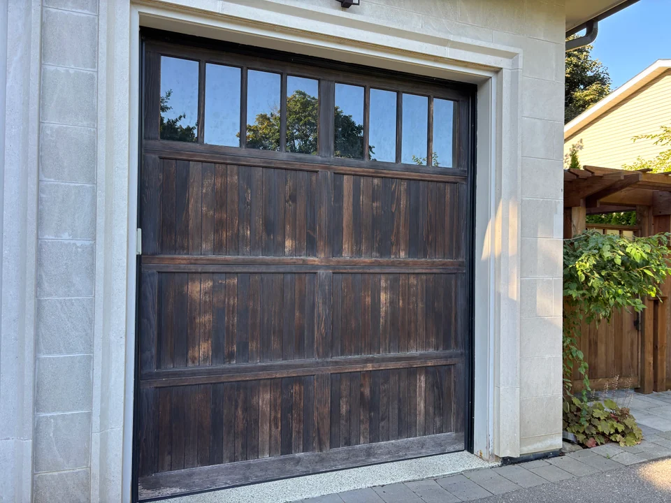 Dark stained wood garage door with visible grain and upper glass panels