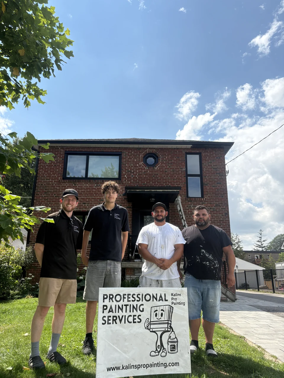 Four Kalins Pro Painting team members outside a painted brick house with their yard sign
