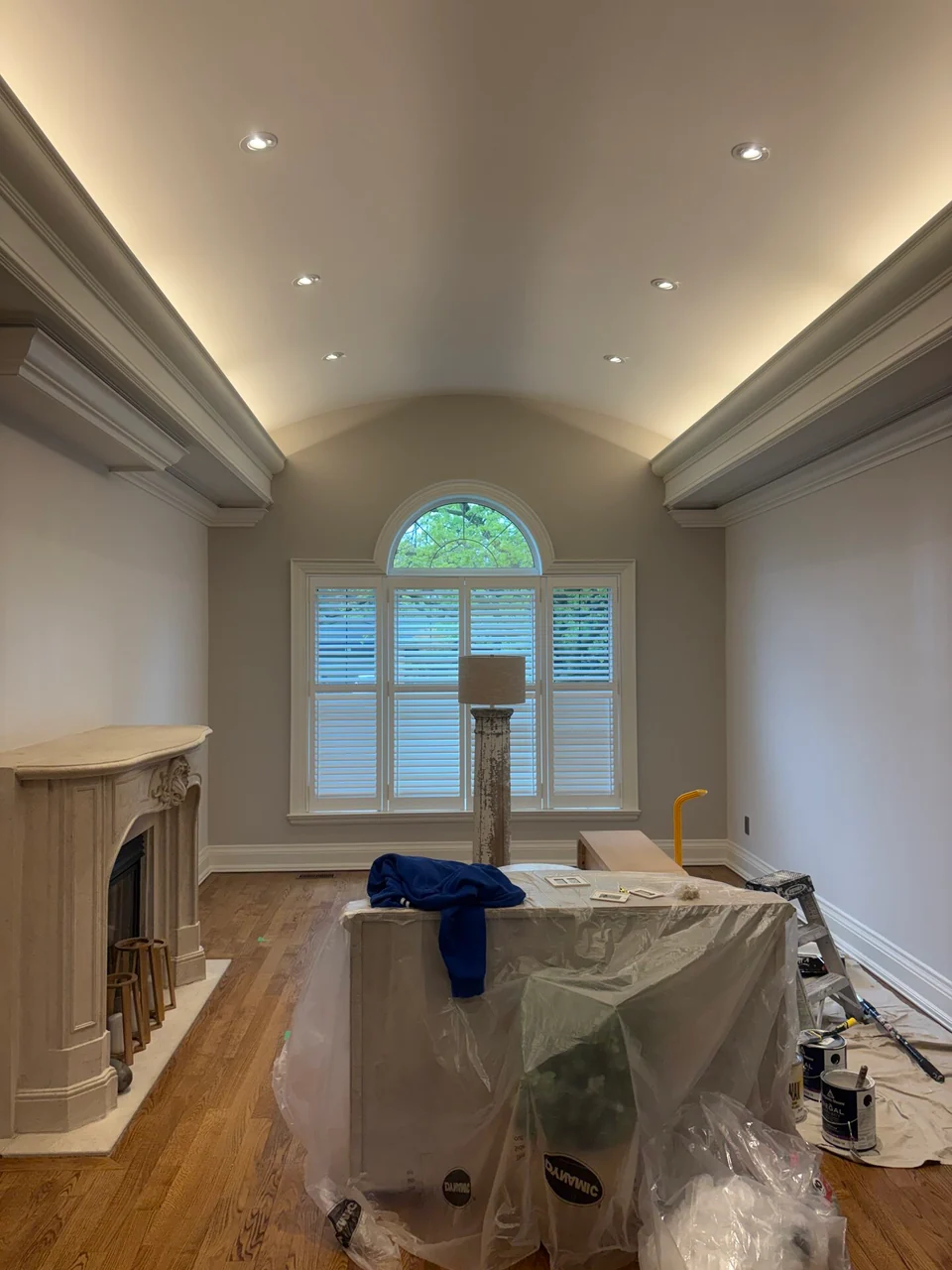 Before: barrel ceiling living room with covered furniture and a fireplace