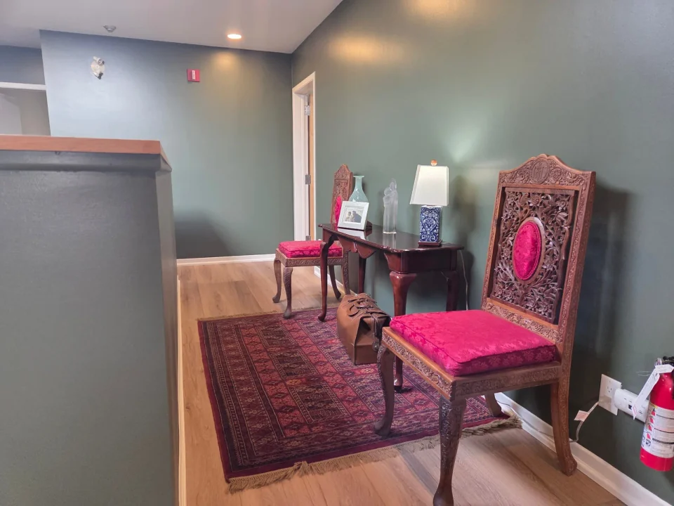 Finished green landing walls with white baseboards and pink upholstered chairs
