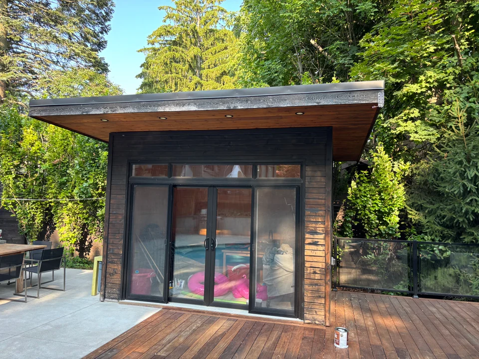Before: weathered wood poolhouse siding around sliding glass doors