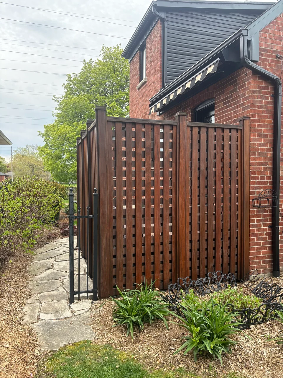 After: warm brown lattice privacy fence and gate beside the house
