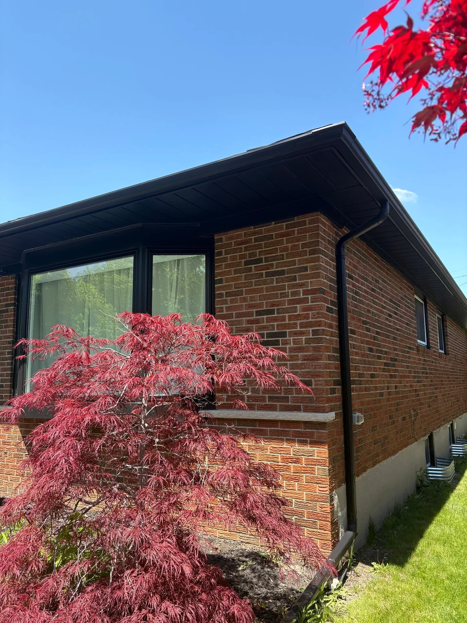 Finished black fascia wrapping the brick corner above large windows