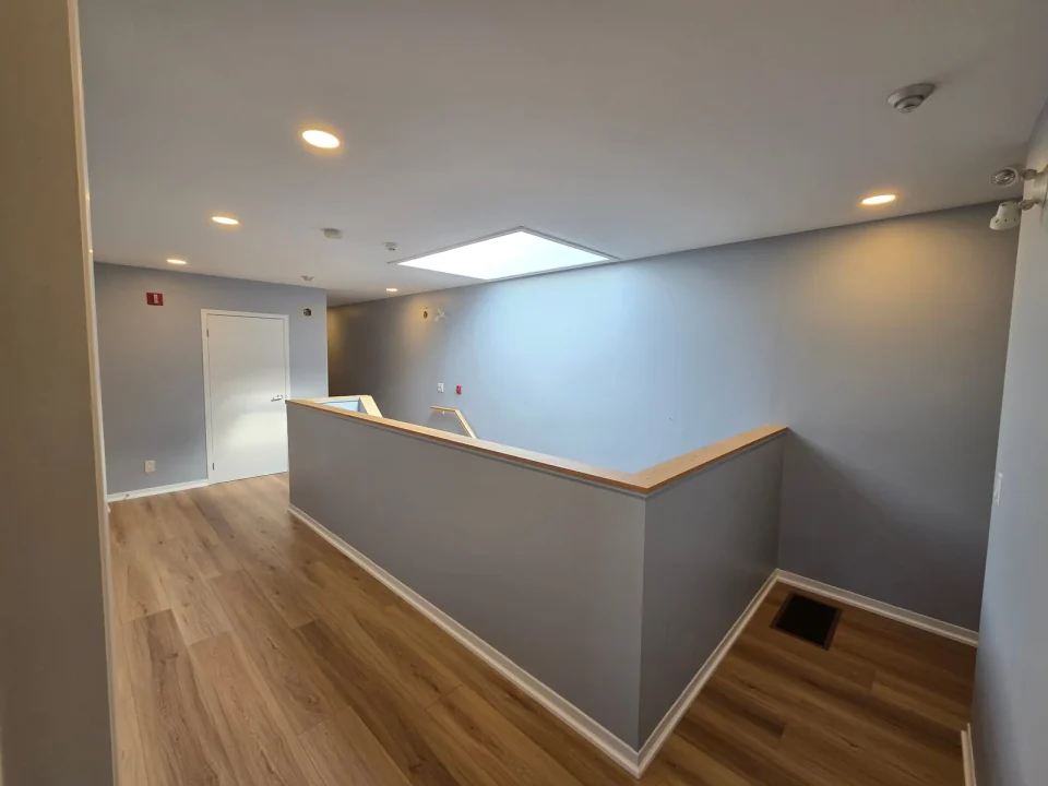 Before: grey stairwell walls around a wood floor landing and skylight